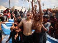 Palestinian children are playing with water and soap to cool themselves down during a heatwave at a temporary camp for the internally displa...