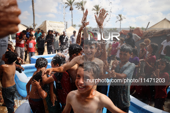 Palestinian children are playing with water and soap to cool themselves down during a heatwave at a temporary camp for the internally displa...