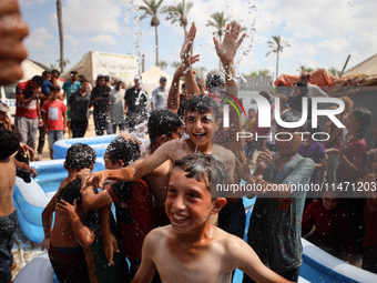 Palestinian children are playing with water and soap to cool themselves down during a heatwave at a temporary camp for the internally displa...