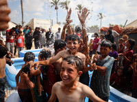 Palestinian children are playing with water and soap to cool themselves down during a heatwave at a temporary camp for the internally displa...