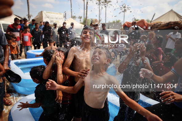 Palestinian children are playing with water and soap to cool themselves down during a heatwave at a temporary camp for the internally displa...