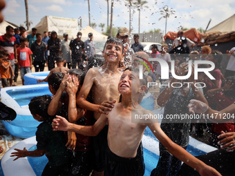 Palestinian children are playing with water and soap to cool themselves down during a heatwave at a temporary camp for the internally displa...