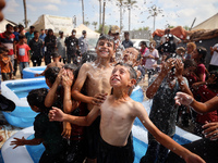 Palestinian children are playing with water and soap to cool themselves down during a heatwave at a temporary camp for the internally displa...