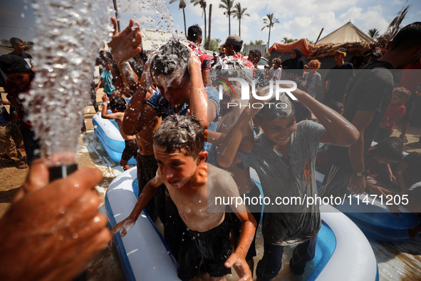 Palestinian children are playing with water and soap to cool themselves down during a heatwave at a temporary camp for the internally displa...