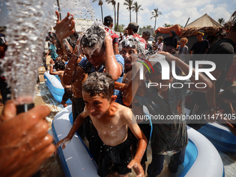 Palestinian children are playing with water and soap to cool themselves down during a heatwave at a temporary camp for the internally displa...