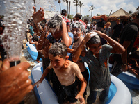 Palestinian children are playing with water and soap to cool themselves down during a heatwave at a temporary camp for the internally displa...