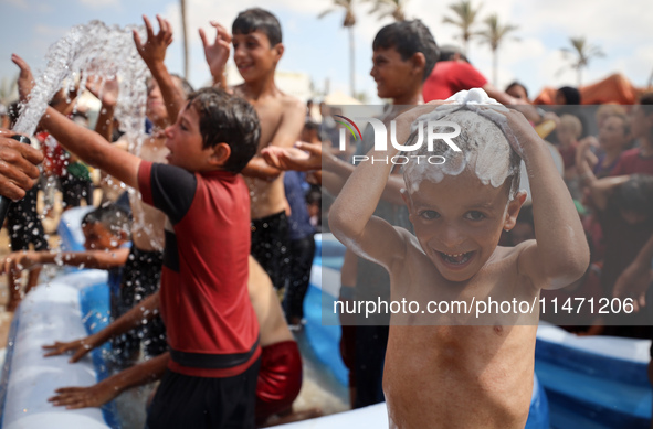 Palestinian children are playing with water and soap to cool themselves down during a heatwave at a temporary camp for the internally displa...