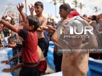 Palestinian children are playing with water and soap to cool themselves down during a heatwave at a temporary camp for the internally displa...