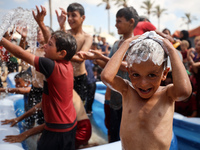 Palestinian children are playing with water and soap to cool themselves down during a heatwave at a temporary camp for the internally displa...