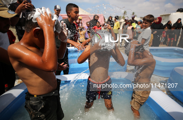 Palestinian children are playing with water and soap to cool themselves down during a heatwave at a temporary camp for the internally displa...