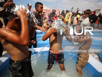 Palestinian children are playing with water and soap to cool themselves down during a heatwave at a temporary camp for the internally displa...