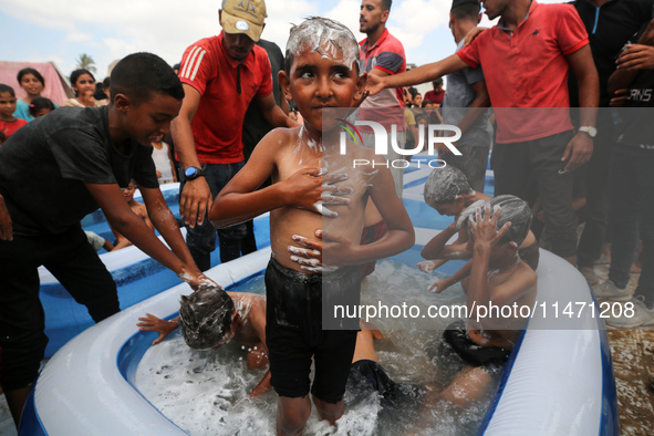 Palestinian children are playing with water and soap to cool themselves down during a heatwave at a temporary camp for the internally displa...