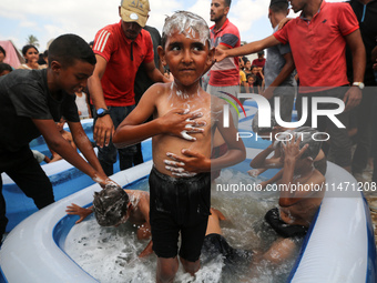 Palestinian children are playing with water and soap to cool themselves down during a heatwave at a temporary camp for the internally displa...