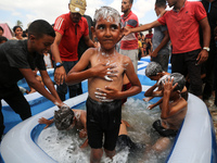 Palestinian children are playing with water and soap to cool themselves down during a heatwave at a temporary camp for the internally displa...