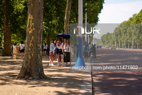 People are finding shelter under umbrellas as the capital is being hit by a heatwave, which is set to bring the temperatures to 35C, in Lond...