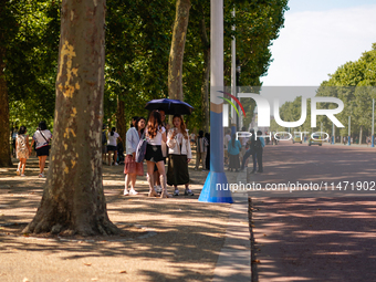 People are finding shelter under umbrellas as the capital is being hit by a heatwave, which is set to bring the temperatures to 35C, in Lond...