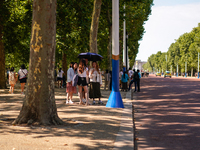 People are finding shelter under umbrellas as the capital is being hit by a heatwave, which is set to bring the temperatures to 35C, in Lond...