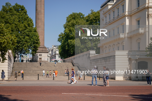 People are walking as the capital is being hit by a heatwave, which is set to bring the temperatures to 35C, in London, England, on August 1...