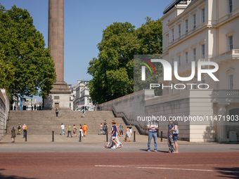 People are walking as the capital is being hit by a heatwave, which is set to bring the temperatures to 35C, in London, England, on August 1...