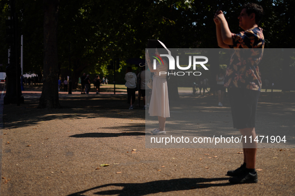 People are finding shelter under umbrellas as the capital is being hit by a heatwave, which is set to bring the temperatures to 35C, in Lond...