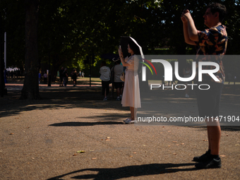 People are finding shelter under umbrellas as the capital is being hit by a heatwave, which is set to bring the temperatures to 35C, in Lond...