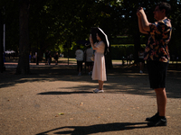 People are finding shelter under umbrellas as the capital is being hit by a heatwave, which is set to bring the temperatures to 35C, in Lond...