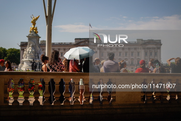 People are finding shelter under umbrellas as the capital is being hit by a heatwave, which is set to bring the temperatures to 35C, in Lond...