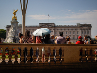 People are finding shelter under umbrellas as the capital is being hit by a heatwave, which is set to bring the temperatures to 35C, in Lond...