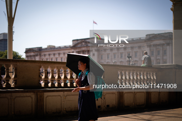 People are finding shelter under umbrellas as the capital is being hit by a heatwave, which is set to bring the temperatures to 35C, in Lond...