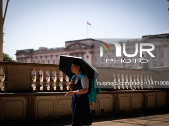 People are finding shelter under umbrellas as the capital is being hit by a heatwave, which is set to bring the temperatures to 35C, in Lond...