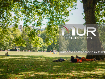 People are resting in the shade in Green Park, as the capital is being hit by a heatwave which is set to bring the temperatures to 35C, in L...