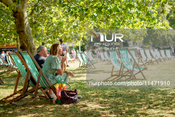 People are sitting to eat ice cream in Green Park, as the capital is being hit by a heatwave which is set to bring the temperatures to 35C,...