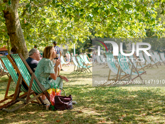 People are sitting to eat ice cream in Green Park, as the capital is being hit by a heatwave which is set to bring the temperatures to 35C,...