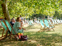 People are sitting to eat ice cream in Green Park, as the capital is being hit by a heatwave which is set to bring the temperatures to 35C,...