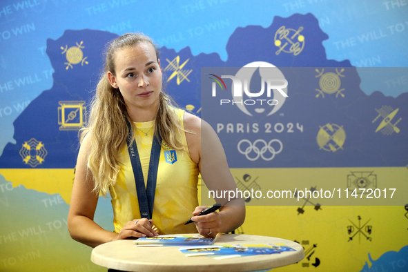 Ukrainian sabre fencer Yuliia Bakastova, who is winning gold in the Women's Sabre Team Gold Medal Match, is signing autographs during the we...