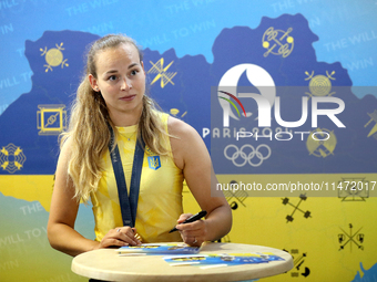 Ukrainian sabre fencer Yuliia Bakastova, who is winning gold in the Women's Sabre Team Gold Medal Match, is signing autographs during the we...