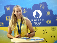 Ukrainian sabre fencer Yuliia Bakastova, who is winning gold in the Women's Sabre Team Gold Medal Match, is signing autographs during the we...