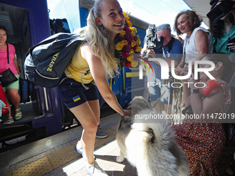 Ukrainian sabre fencer Yuliia Bakastova, who is winning gold in the Women's Sabre Team Gold Medal Match, is petting a dog on the platform of...