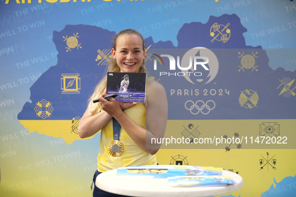 Ukrainian sabre fencer Yuliia Bakastova, who is winning gold in the Women's Sabre Team Gold Medal Match, is signing autographs during the we...