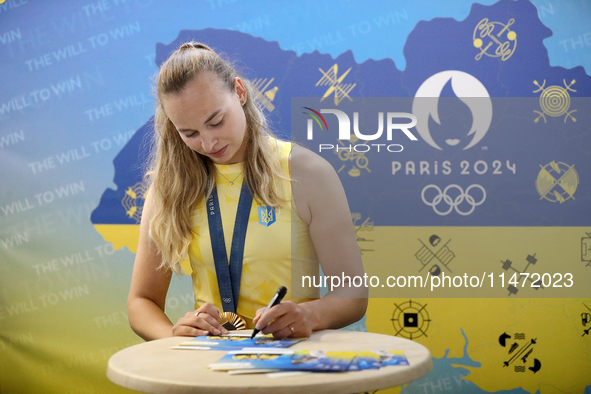 Ukrainian sabre fencer Yuliia Bakastova, who is winning gold in the Women's Sabre Team Gold Medal Match, is signing autographs during the we...