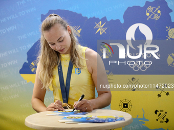 Ukrainian sabre fencer Yuliia Bakastova, who is winning gold in the Women's Sabre Team Gold Medal Match, is signing autographs during the we...