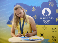 Ukrainian sabre fencer Yuliia Bakastova, who is winning gold in the Women's Sabre Team Gold Medal Match, is signing autographs during the we...