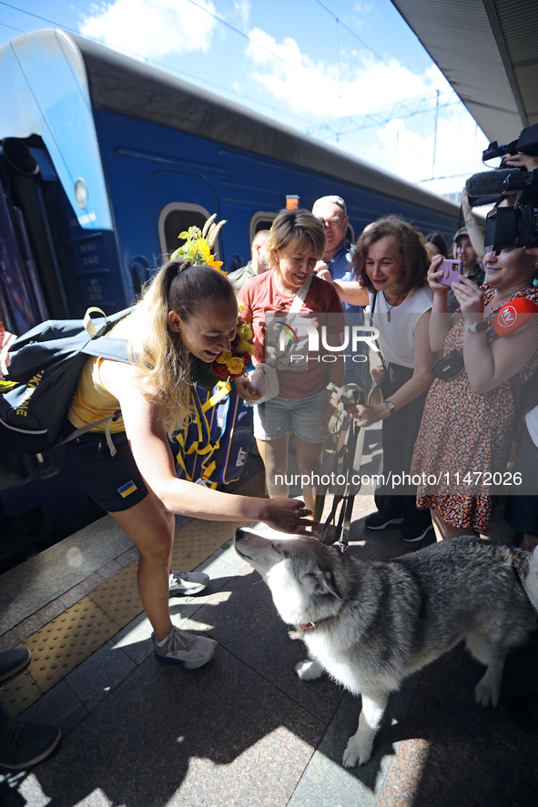 Ukrainian sabre fencer Yuliia Bakastova, who is winning gold in the Women's Sabre Team Gold Medal Match, is petting a dog on the platform of...