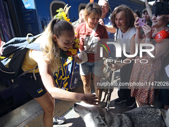 Ukrainian sabre fencer Yuliia Bakastova, who is winning gold in the Women's Sabre Team Gold Medal Match, is petting a dog on the platform of...