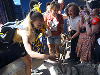 Ukrainian sabre fencer Yuliia Bakastova, who is winning gold in the Women's Sabre Team Gold Medal Match, is petting a dog on the platform of...