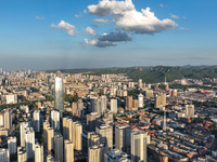 The blue sky and white clouds are silhouetted against urban buildings in Jinan, China, on August 12, 2024. (