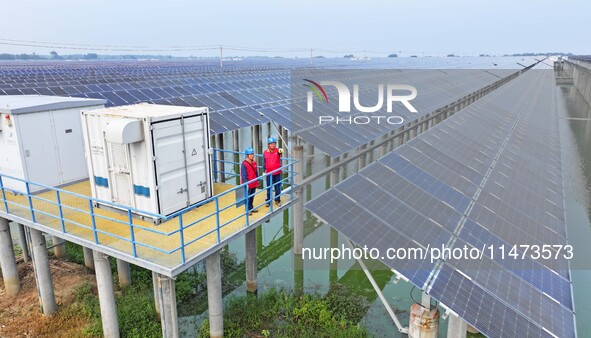 Operation and maintenance personnel are inspecting the operating power generation facilities at the ''fishery-solar hybrid project'' photovo...