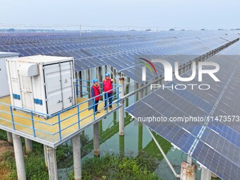 Operation and maintenance personnel are inspecting the operating power generation facilities at the ''fishery-solar hybrid project'' photovo...