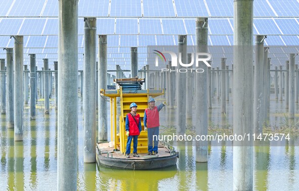 Operation and maintenance personnel are inspecting the operating power generation facilities at the ''fishery-solar hybrid project'' photovo...