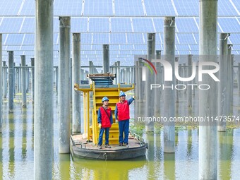 Operation and maintenance personnel are inspecting the operating power generation facilities at the ''fishery-solar hybrid project'' photovo...